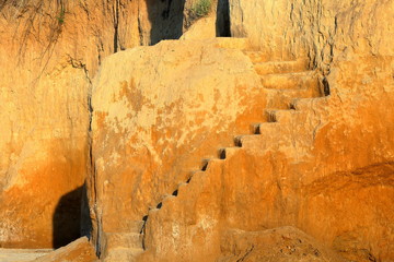 A steep climb up srairs carved in cliff of loamy soil. Staircase, carved in clay crag