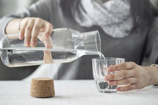 Young woman pouring water from bottle to glass
