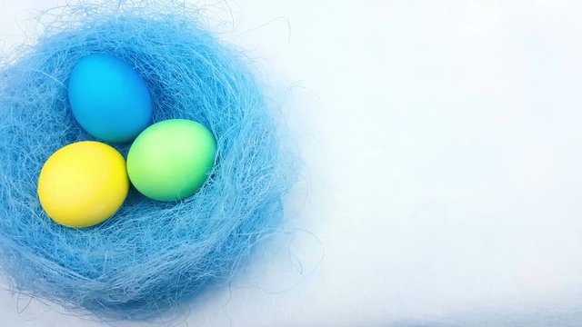 Easter color eggs in nest on pastel blue background. 