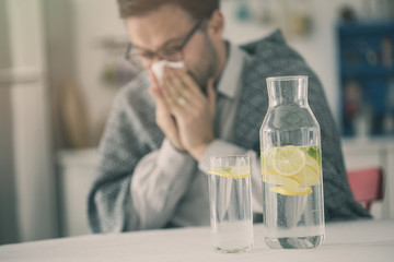 Sick young man and water with slide lemon bottle