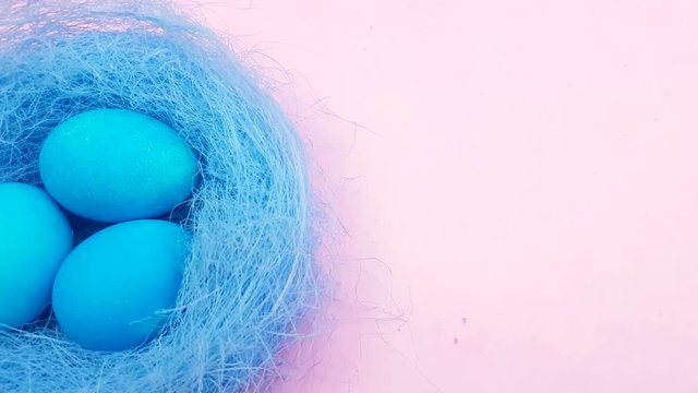 Color easter eggs in nice nest on pastel pink background.