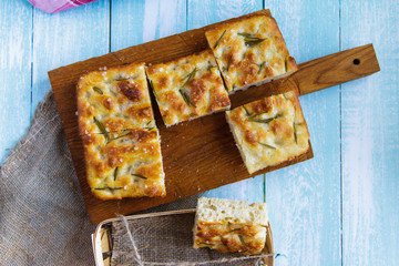 Traditional Italian focaccia with rosemary, tomato on a cutting board