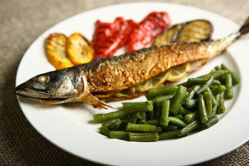 Healthy and proper food, grilled fish and vegetables with lemon and green beans on a white plate. Low-calorie food