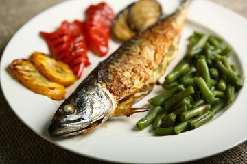 Healthy and proper food, grilled fish and vegetables with lemon and green beans on a white plate. Low-calorie food. Close-up