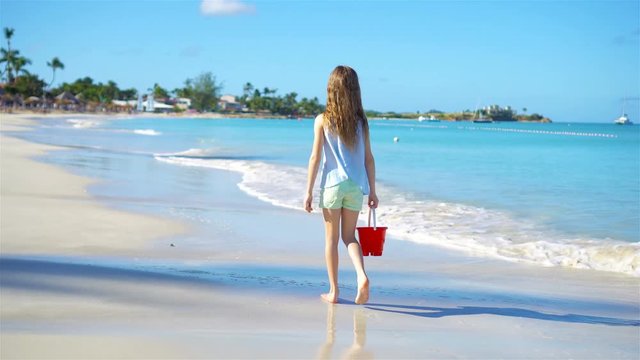 Adorable little girl with busket walking on beach vacation