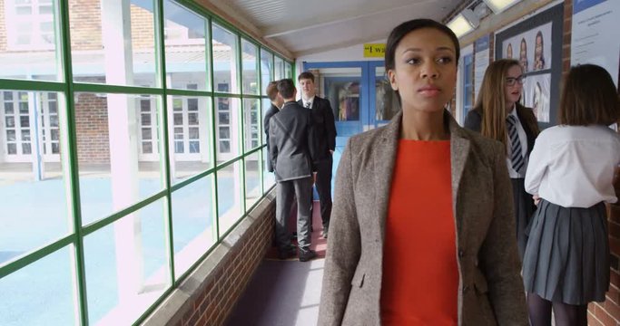 4K Serious high school teacher walking through hallway & disciplining students. Slow motion