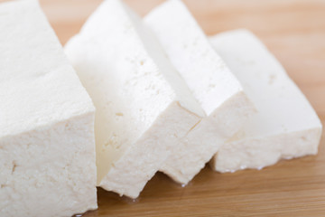 Tofu piece and cubes on chopping board.  Closeup.
