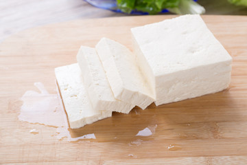 Tofu piece and cubes on chopping board.  Closeup.
