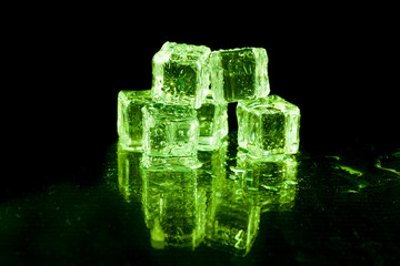 Green ice cubes on black background.