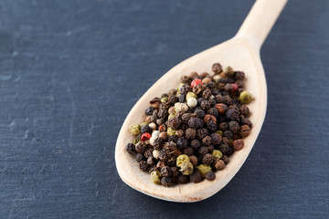 black pepper peas in a spoon on a stone background