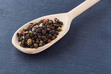 black pepper peas in a spoon on a stone background
