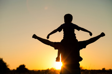 Father and son playing in the park at the sunset time.