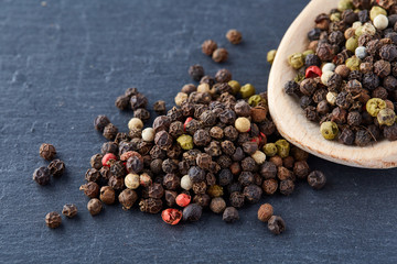 black pepper peas in a spoon on a stone background