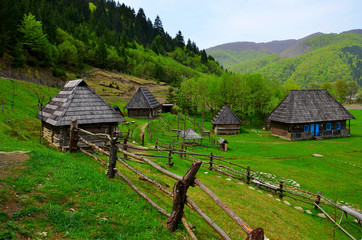 Old wooden houses. Traditional old wooden house in Carpathian mountains. Dirt road leading to lonely distant village with old wooden houses in mountain gorge. Wooden vintage house in traditional style