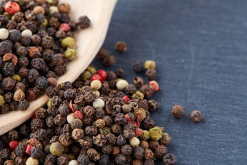 black pepper peas in a spoon on a stone background