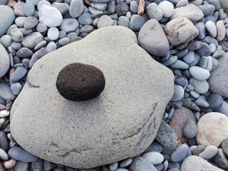 Big sea pebble stone or rock rounded shape as frame on beach. Different pebble stone natural abstract texture or background frame. Black pebble stone frame on seacoast. Pebble stone in gravel frame