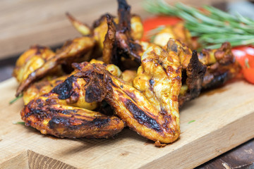 Grilled chicken wings on a light oak surface.
