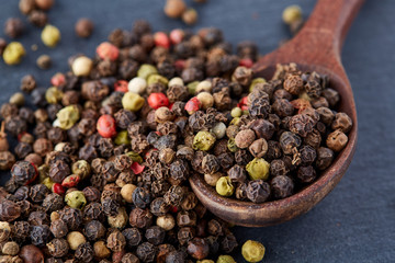 black pepper peas in a spoon on a stone background