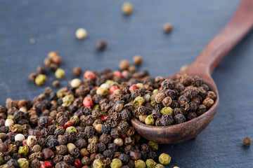 black pepper peas in a spoon on a stone background