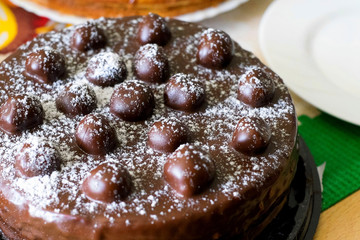 Chocolate cherries cream cake. Close-up chocolate cake with sugar icing and cherry decoration. Chocolate cake with cherries on party dinner table background. Cake with cherries covered chocolate glaze