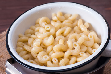 Fresh cooked Pasta in a sieve on a wooden table