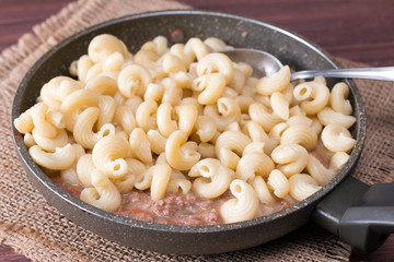 Pasta in ceramic form with meat pate in a frying pan