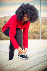 Beautiful athlete woman tying shoes to run in the park