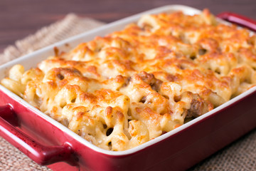 Cheese pasta baked in a ceramic form on background wooden table
