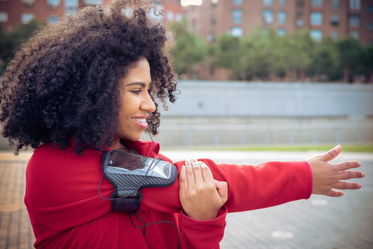 Beautiful athlete woman streaching before running with earphones, smart watch and mobile app in the park