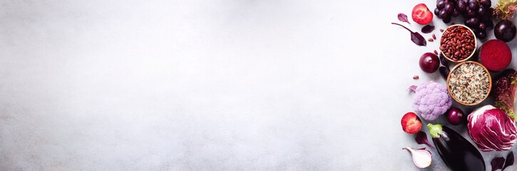 Purple vegetables, fruits on grey background. Violet eggplant, beets, cauliflower, purple beans, plums, onion, grape, quinoa, rice. Ingredients for cooking, copy space, top view, flat lay. Banner