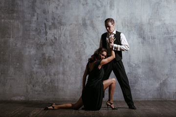 Fototapeta na wymiar Young pretty woman in black dress and man dance tango