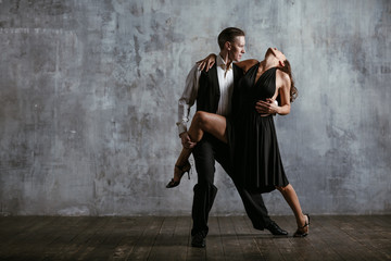Young pretty woman in black dress and man dance tango