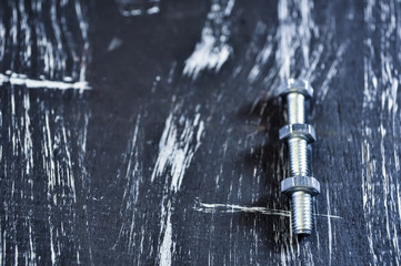 Nuts for repairs lying on a wooden table. Iron nuts and screws f