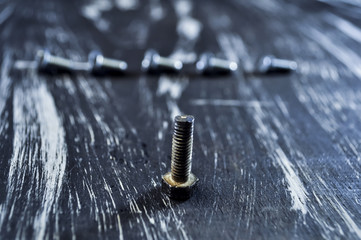 Nuts for repairs lying on a wooden table. Iron nuts and screws f