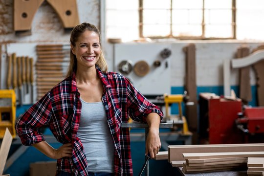 Happy female carpenter standing in workshop