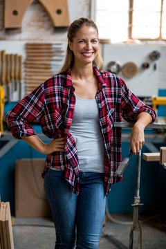 Happy female carpenter standing in workshop
