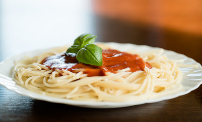 Italian pasta spaghetti topped with a tomato and fresh basil