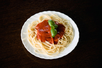 Italian pasta spaghetti topped with a tomato and fresh basil