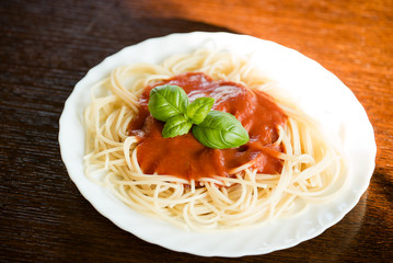 Italian pasta spaghetti topped with a tomato and fresh basil