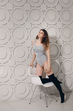 Young beautiful brunette woman with perfect body in sexy grey underwear and stockings, posing on gray background. Studio shoot