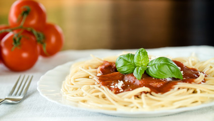 Italian pasta spaghetti topped with a tomato and fresh basil