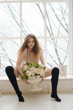 Sexy young brunet posing on window sill