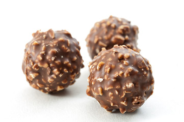 Chocolates and sweet candy concept with closeup on hazelnut and chocolate truffles isolated on white background