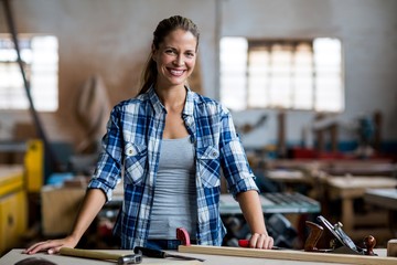 Portrait of female carpenter standing with work tool