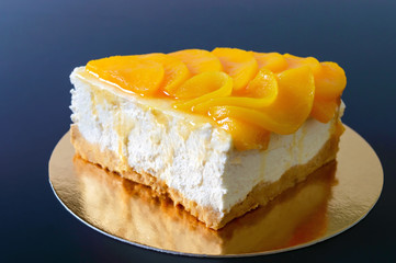 Delicate souffle with juicy peaches. A large delicious piece of cake on a golden stand on a black background.
