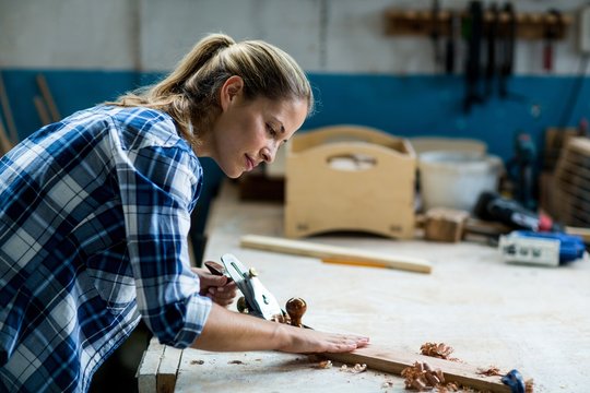 Female carpenter levelling a timber with jack plane