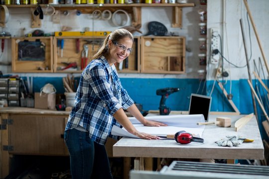 Female carpenter with blueprint in workshop