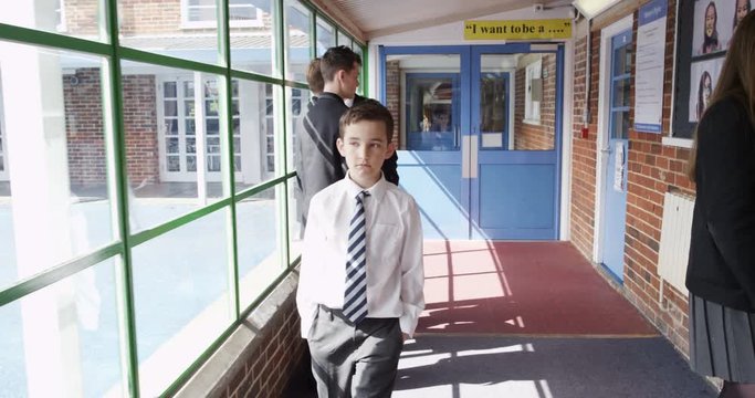 4K Young boy at school with no friends, walking through hallway with other kids sneering at him. Slow motion