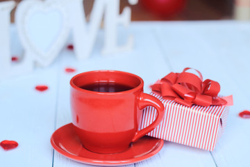 Cup of coffee and gift on blurred background.