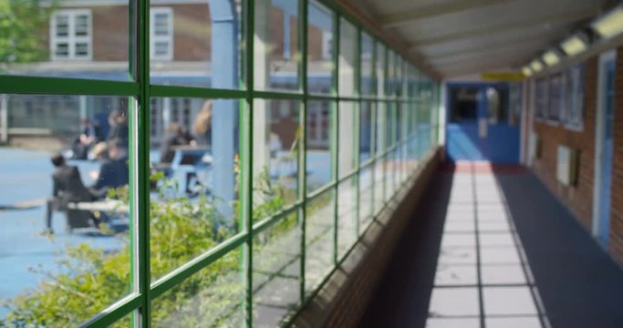 4K View through school window of children enjoying break time outdoors. Slow motion